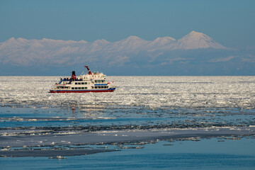 知床連山と流氷を割り進砕氷観光船