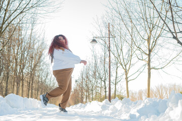 Smiling chubby redhead woman running in park in winter. 