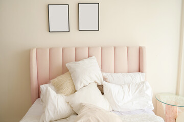 Warm and cozy interior of bedding room space with pink bed, mock up poster frame. Cozy home decor.