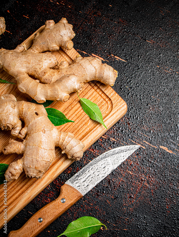 Sticker ginger on a cutting board with a knife.