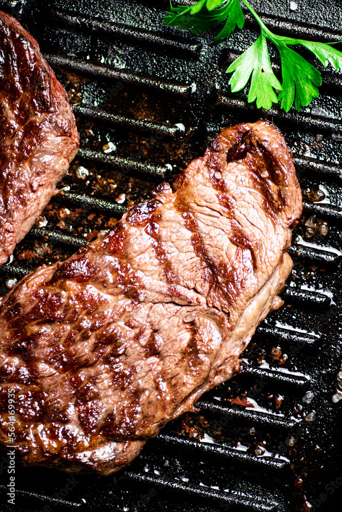 Poster grilled steak with parsley in a frying pan.