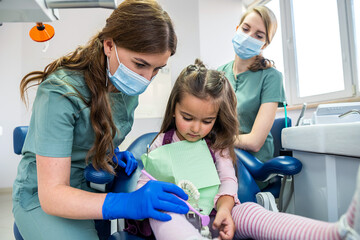 A small child at a dentist's appointment, the doctor shows and tells how to brush your teeth