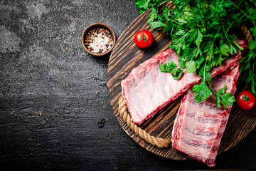 Raw ribs with greenery on a wooden tray. 