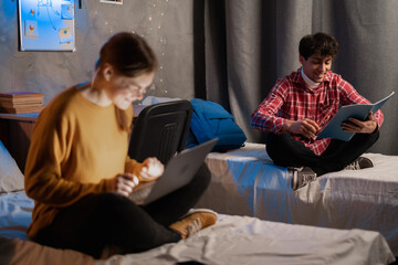 Fototapeta premium College students guy and girl studying in university dormitory talking preparing for exam.