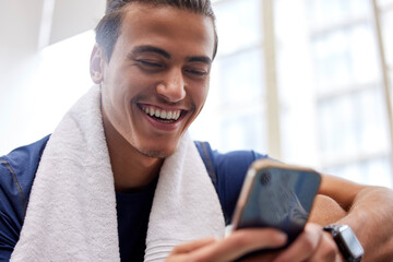 Fototapeta na wymiar Man relax, fitness and smartphone in gym, smile and rest after workout, training and typing for social media. Male, athlete and guy with cellphone, break and connection for chatting and with towel