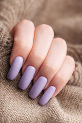 Girl's hands with a soft purple manicure.