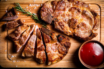 Grilled pork steak cut into pieces with tomato sauce. 