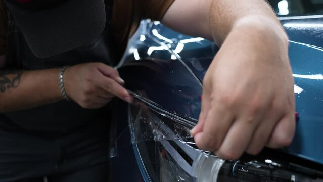 The master in the car service applies an armor film to the car. 