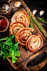 Grilled sausages on a cutting board with tomato sauce, garlic and herbs. 