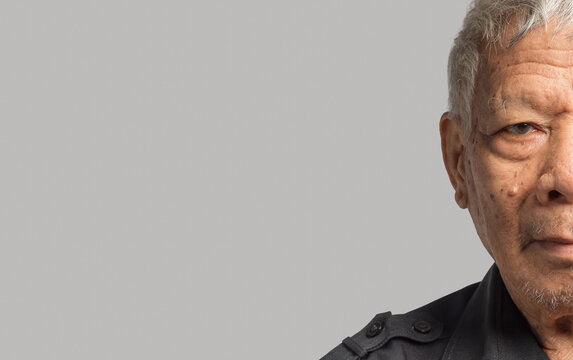 Close-up of senior man half face standing on a gray background - Powered by Adobe