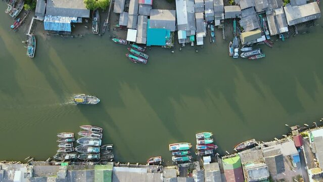 Aerial drone view flying over fishing boat speeding through fisherman village at Pak Nam Sichon, the estuary area of Gulf of Thailand in Chumphon province, Thailand. 4K Footage video
