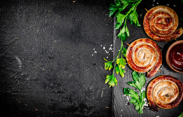 Grilled sausages on a stone board with tomato sauce and parsley. 