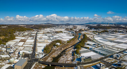 Aerial view of snow covered rice fields in Japanese countryside on sunny winter day