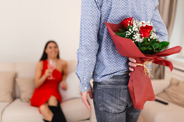 Happy woman looking at her boyfriend holding bouquet of roses behind his back. Man holding flowers behind his back to surprise his girlfriend, romantic happy couples on 8 March happy women's day