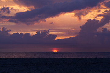 Naklejka na ściany i meble Coastal landscape with dramatic dark sky over ocean on a sunset