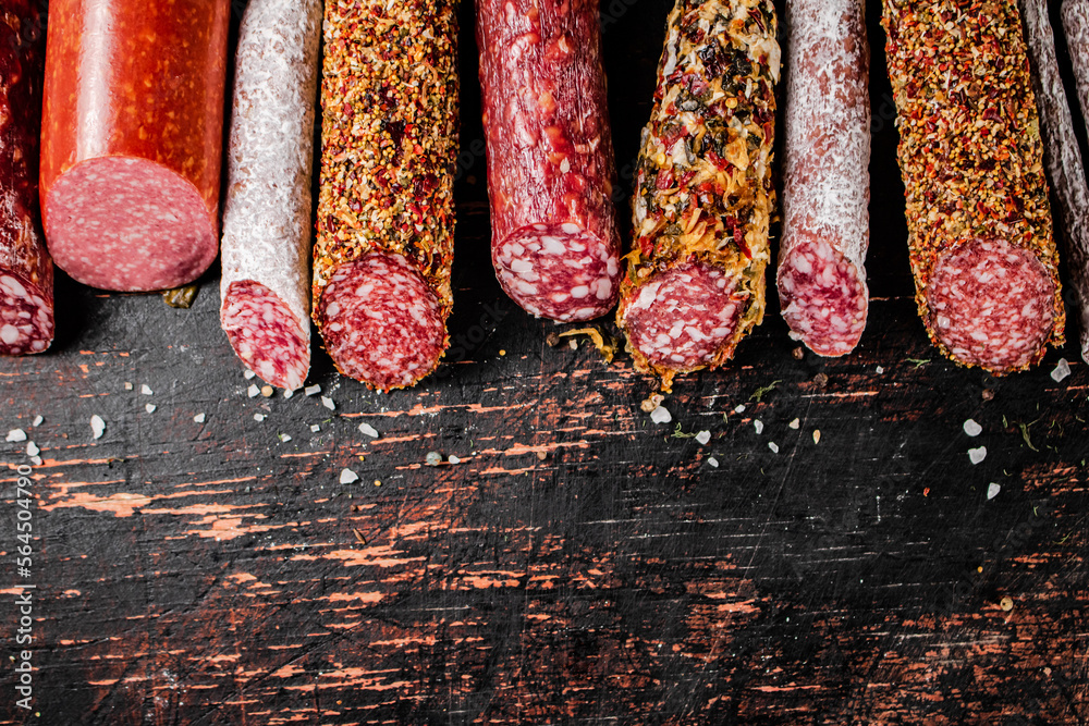 Sticker various salami sausage on the table in a row.