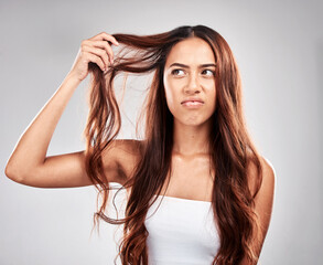 Woman, hair care and angry face in studio for luxury wellness, damaged hair loss or frustrated. Upset model, salon stress and messy hairstyle mistake, beauty problem or split end in grey background