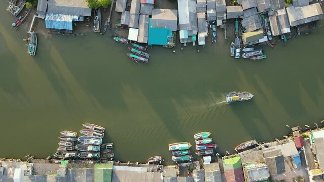 Aerial drone view flying over fishing boat speeding through fisherman village at Pak Nam Sichon, the estuary area of Gulf of Thailand in Chumphon province, Thailand. 4K Footage video