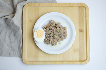 boiled green buckwheat on a plate with a boiled egg, healthy ready-made food