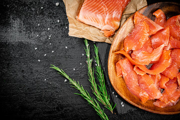Salted salmon on a wooden plate with greens. 