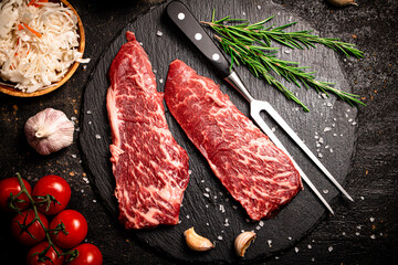 Raw steak on a stone board. On a black background.