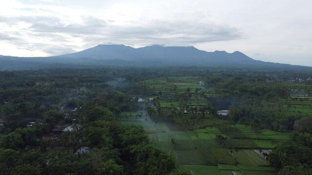 Moody cinematic aerial view of the morning countryside scenery against the backdrop of Mount Raung