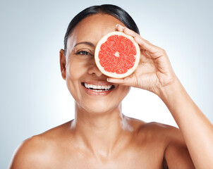 Grapefruit, woman and vitamin c beauty, portrait and skincare wellness on studio background. Happy model, face and citrus fruits for natural cosmetics, detox and nutrition for healthy aesthetic glow