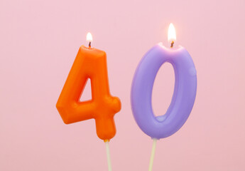 Birthday candles burning on pink background, number 40