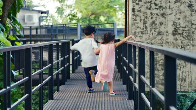 2 children Asian brothers and sisters Run hand in hand on outdoor playground. There's lot of fun, laughs, of both of them.