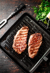 Grilled steak with parsley in a frying pan. 