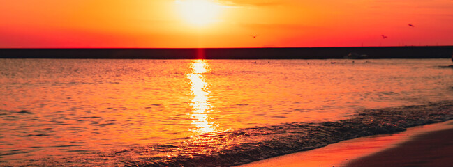 Reflection of sunlight over sea surface at sunset. Orange and gold blue sky. Dramatic Yellow sun...