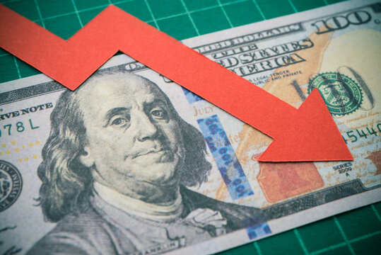 Red graph falling down on US dollar banknote background. The Federal Reserve ( FED ) increase % interest rates to fix inflation crisis. World global economy recession and stagflation concept.