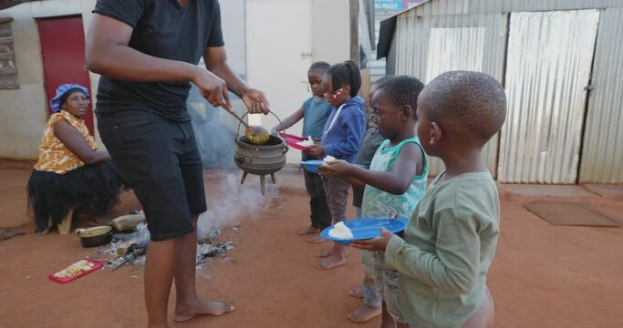 Poverty in Africa. Hungry Black African children holding out plates while a charity organisation distributes food