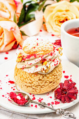 The concept of romantic tea. French Shu cake, hibiscus tea, bouquet of roses, festive decor