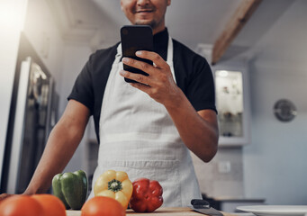 Cooking vegetables, phone and man in kitchen while online with house wifi connection for learning on food blog. Chef person with mobile app for online recipe for home food for vegan or healthy eating