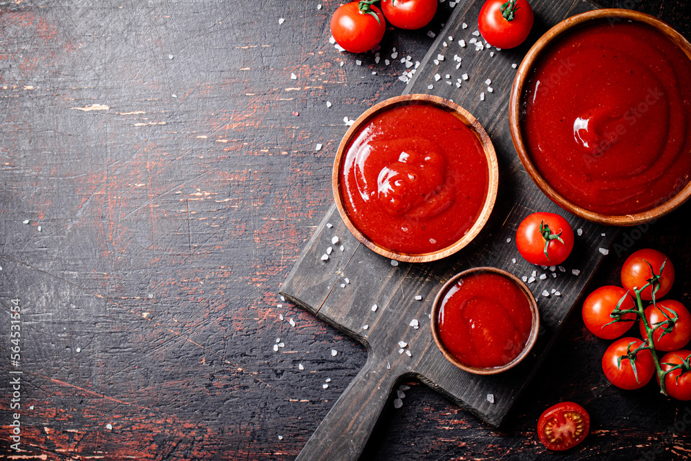 Wall mural Tomato sauce on a wooden cutting board with pieces of salt. 