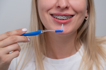 Caucasian woman cleaning her teeth with braces using a brush. Cropped portrait. 