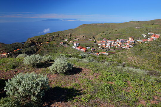Spectacular view towards the village of Arure, La Gomera, Canary Islands, Spain, with green plants in the foreground and La Palma island in the background