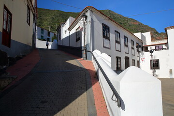 Cobbled streets and whitewashed houses in Hermigua, La Gomera, Canary Islands, Spain, with the monastic church of the Dominican monastery (El Convento de Santo Domingo) on the right side - obrazy, fototapety, plakaty