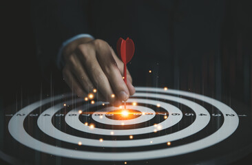 Businessman holding a red dart aiming precisely at the center of the target board.	
