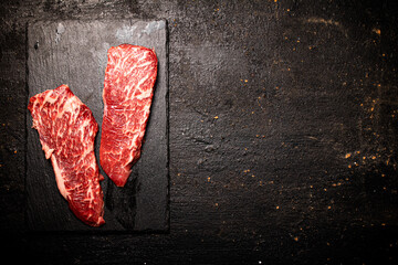 Raw steak on a stone board. On a black background.