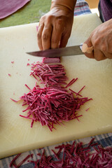 Handmade, delicious Turkish pasta (noodles) with beetroot. A woman's hand is cutting noodles.