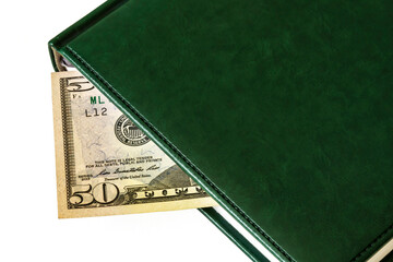 Against a light background lies a diary and part of a 50 dollar bill