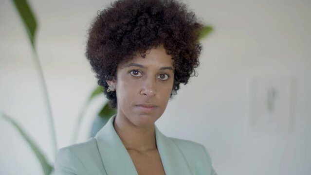 Portrait Shot Of Young African American Woman Indoors. Serious Black Lady With Short Curly Hair Looking At Camera. Lifestyle, Office, Profession Concept