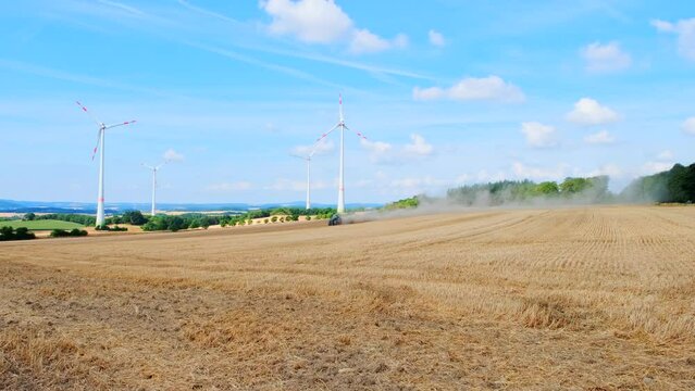 Tractor working in the field against the backdrop of rotating windmills