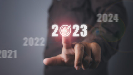 Man pressing 2023 virtual screen with arrow up business target and goal.