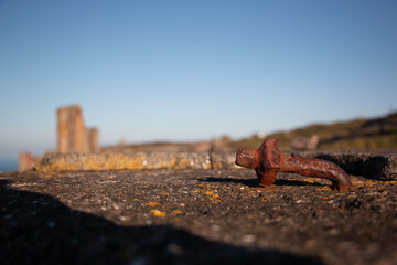 Rusty peg in concrete wall with ruined mining building behind