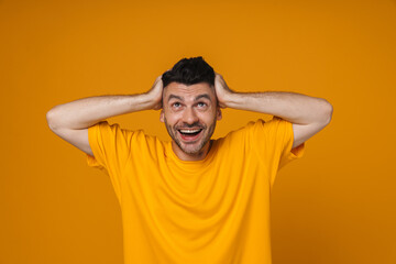 Fototapeta na wymiar Man smiling and grabbing his head isolated over yellow background
