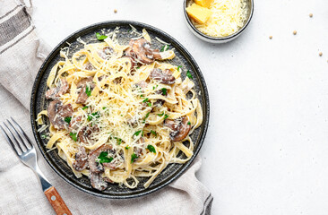 Tagliatelle pasta with mushrooms and parmesan cheese on plate with parsley on grey stone table background, top view. Italian food concept