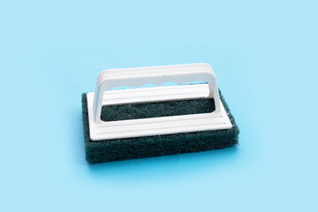 Green scrub sponge on blue background.